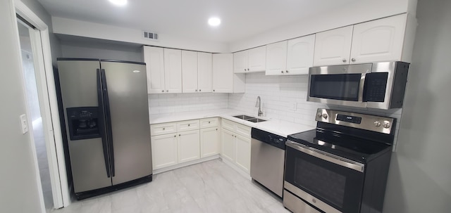 kitchen featuring decorative backsplash, white cabinetry, light tile patterned floors, stainless steel appliances, and sink