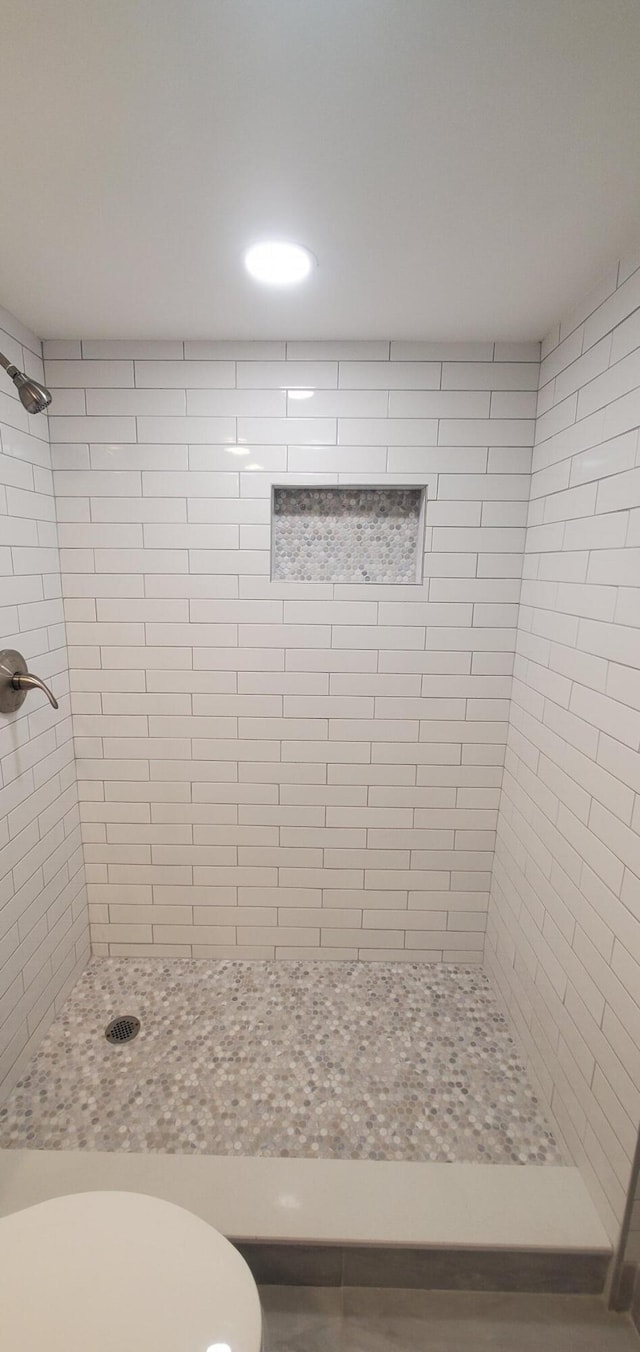 bathroom with toilet and a tile shower