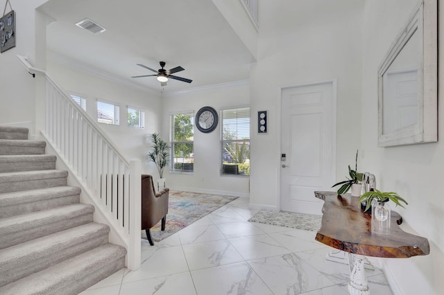 tiled entryway featuring ceiling fan and crown molding