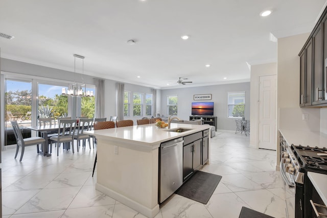 kitchen with stainless steel appliances, sink, an island with sink, ceiling fan with notable chandelier, and hanging light fixtures