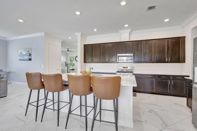 kitchen with range, ornamental molding, dark brown cabinets, and a center island