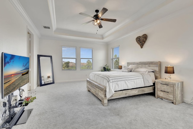 bedroom featuring ceiling fan, ornamental molding, multiple windows, and a tray ceiling