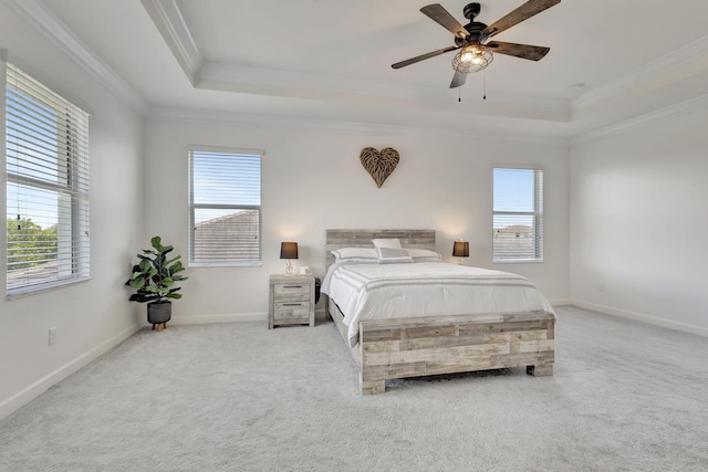 carpeted bedroom with a raised ceiling, ornamental molding, and multiple windows