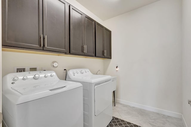 laundry area with washer and clothes dryer, light tile patterned floors, and cabinets