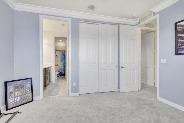 unfurnished bedroom with light carpet, a closet, ensuite bath, and ornamental molding