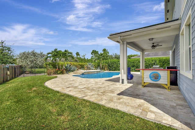 view of swimming pool with ceiling fan, a patio, and a yard