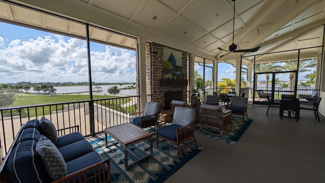 sunroom with ceiling fan and a water view