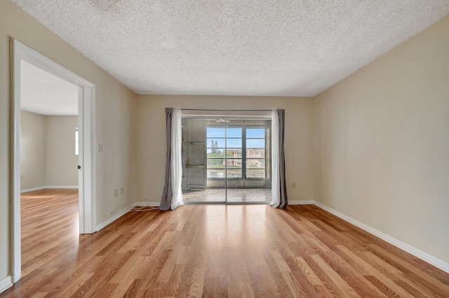 unfurnished room with a textured ceiling and light hardwood / wood-style flooring