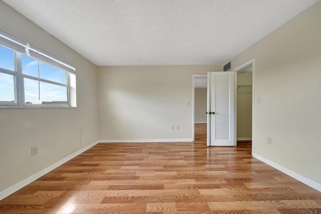 empty room with light hardwood / wood-style flooring and a textured ceiling