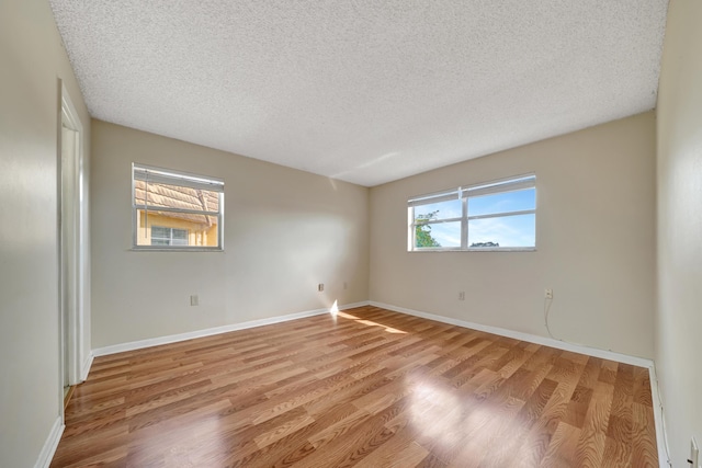 unfurnished room with a textured ceiling and light hardwood / wood-style floors