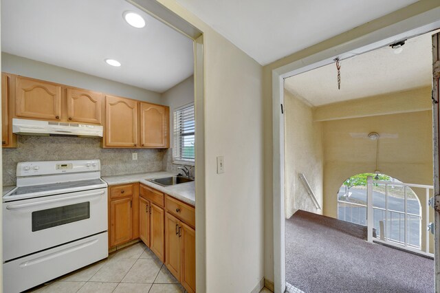 kitchen with electric stove, light brown cabinetry, light tile patterned floors, decorative backsplash, and sink