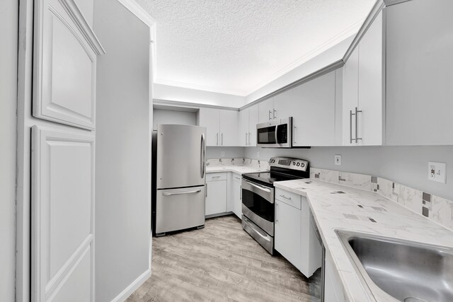 kitchen featuring a textured ceiling, appliances with stainless steel finishes, sink, white cabinetry, and light hardwood / wood-style floors