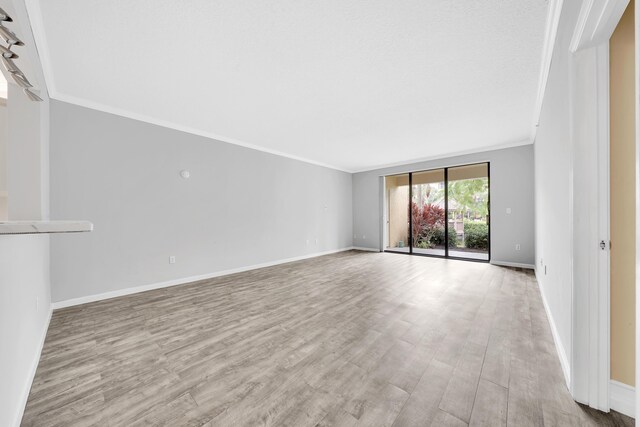 empty room with ornamental molding and light hardwood / wood-style floors