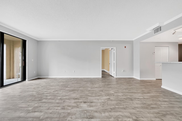 empty room featuring a textured ceiling, ornamental molding, and hardwood / wood-style flooring