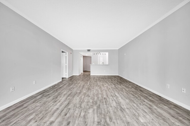 unfurnished living room featuring crown molding and hardwood / wood-style flooring