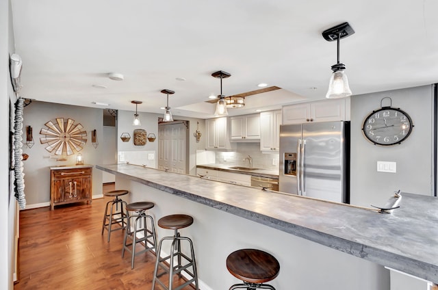 kitchen with stainless steel appliances, wood-type flooring, a kitchen bar, backsplash, and sink