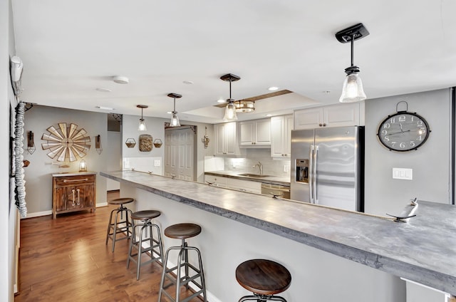 kitchen with a breakfast bar, sink, appliances with stainless steel finishes, pendant lighting, and white cabinets