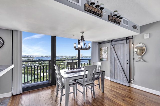 dining area with wood-type flooring, a barn door, plenty of natural light, and a water view