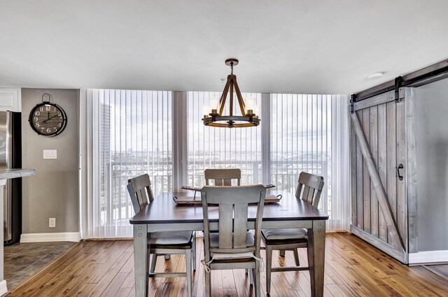 dining space featuring an inviting chandelier, a barn door, and wood-type flooring