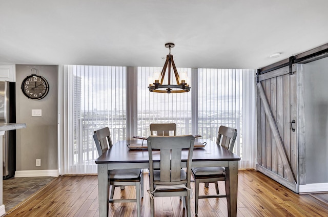 dining area with wood-type flooring, a wealth of natural light, and a notable chandelier