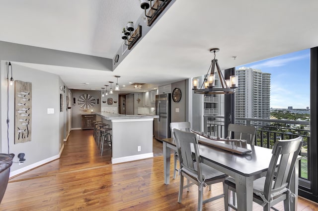 dining room with hardwood / wood-style flooring, floor to ceiling windows, and an inviting chandelier