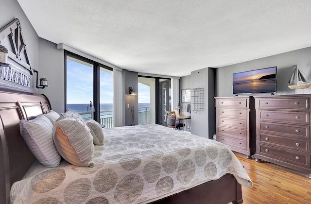 bedroom with light wood-type flooring, a textured ceiling, and access to outside