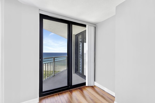 spare room with a water view, expansive windows, a textured ceiling, and light wood-type flooring