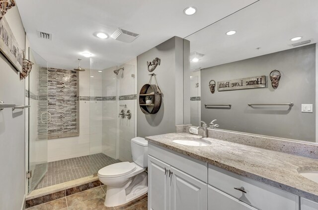 bathroom with a shower with door, double sink vanity, toilet, and tile patterned flooring