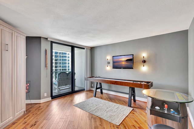 game room featuring light hardwood / wood-style flooring, a textured ceiling, and floor to ceiling windows