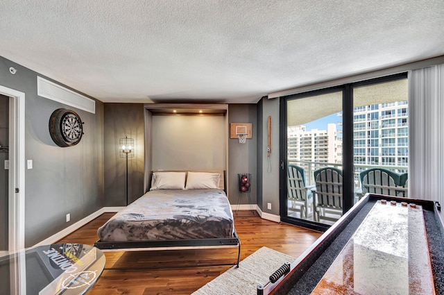 bedroom featuring a textured ceiling, hardwood / wood-style floors, and access to exterior