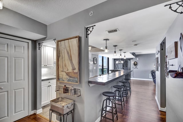 kitchen with a barn door, kitchen peninsula, a breakfast bar area, and white cabinets