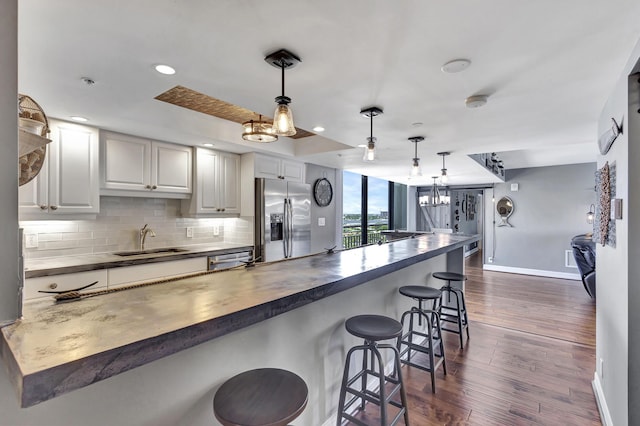 kitchen featuring sink, appliances with stainless steel finishes, white cabinets, a kitchen bar, and decorative light fixtures