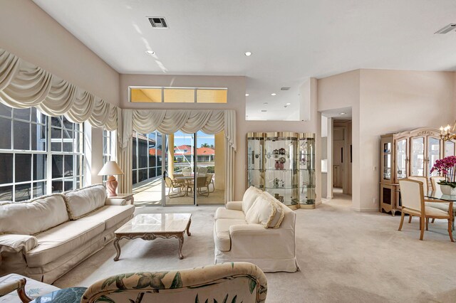 living room with a high ceiling, a chandelier, and light carpet