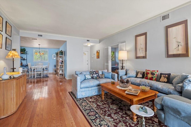 living room featuring a notable chandelier, crown molding, and hardwood / wood-style flooring