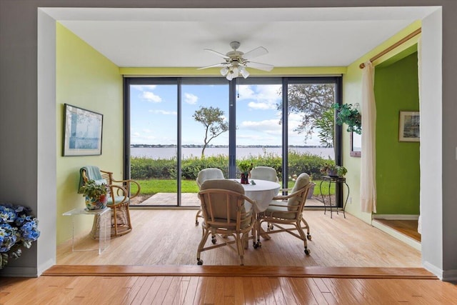 sunroom featuring a water view and ceiling fan