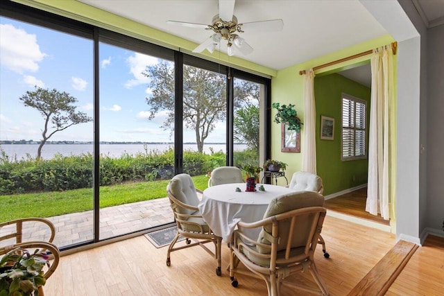 sunroom / solarium featuring a water view and ceiling fan