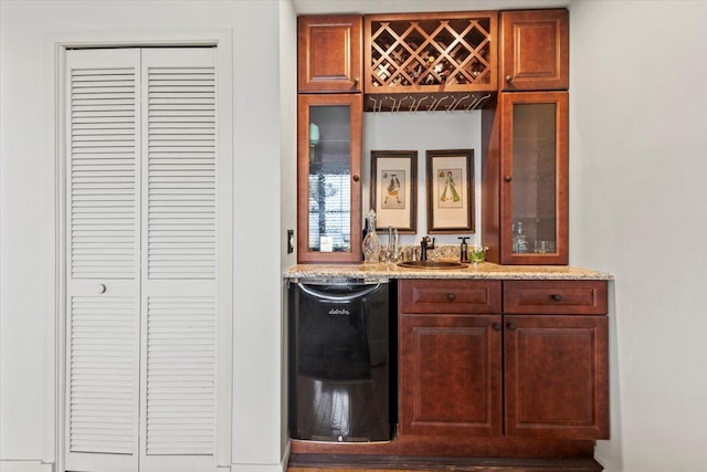 bar featuring black dishwasher, sink, and light stone counters