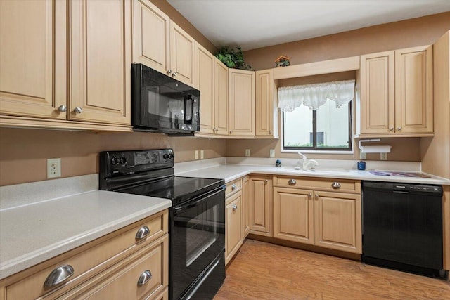 kitchen featuring sink, black appliances, light hardwood / wood-style flooring, and light brown cabinets