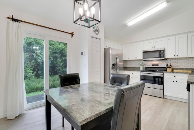 kitchen featuring lofted ceiling, light wood-type flooring, stainless steel appliances, and plenty of natural light