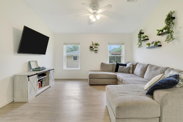 living room with light hardwood / wood-style flooring, ceiling fan, and a wealth of natural light