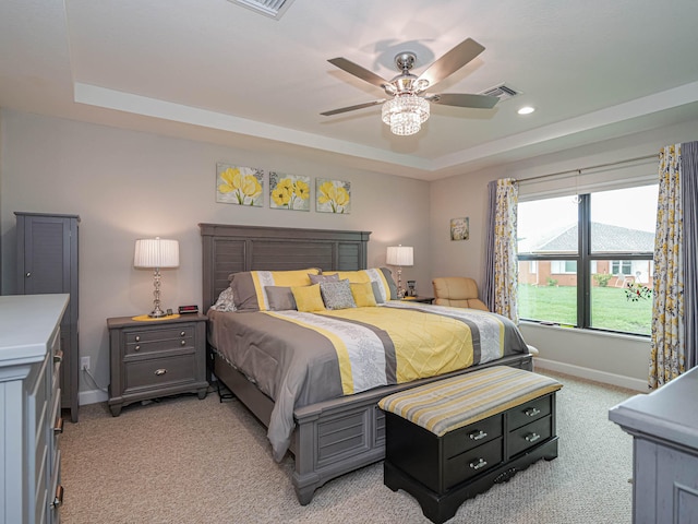 carpeted bedroom featuring ceiling fan and a raised ceiling