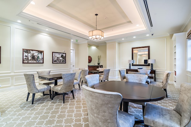 dining area with a raised ceiling, light colored carpet, and crown molding