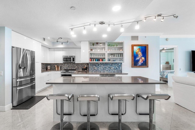 kitchen featuring white cabinetry, backsplash, ornamental molding, stainless steel appliances, and a breakfast bar