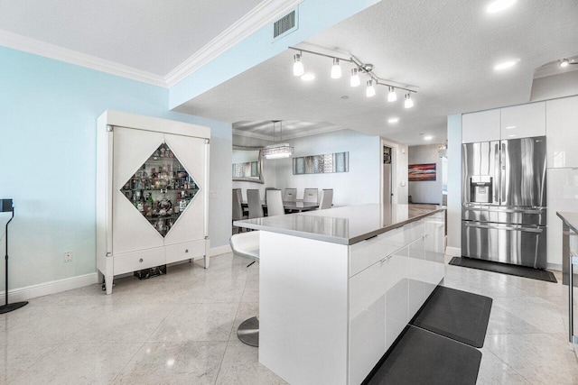 kitchen featuring a textured ceiling, stainless steel fridge with ice dispenser, white cabinets, crown molding, and track lighting