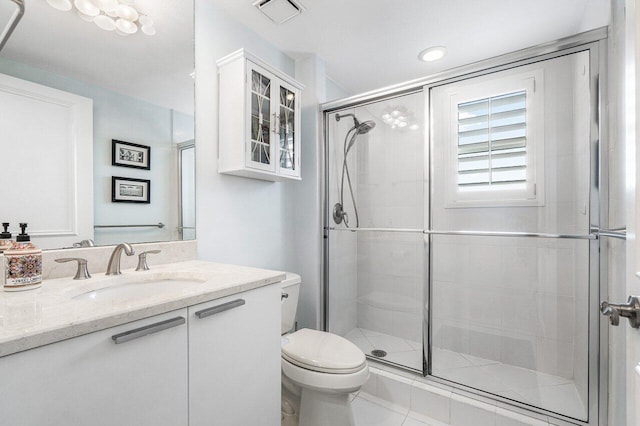 bathroom with a shower with door, toilet, vanity, and tile patterned flooring