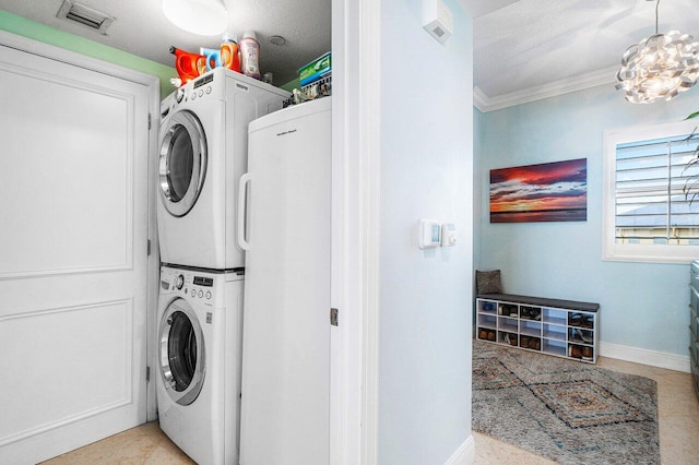 laundry area with a textured ceiling, a chandelier, stacked washer / drying machine, light tile patterned floors, and ornamental molding