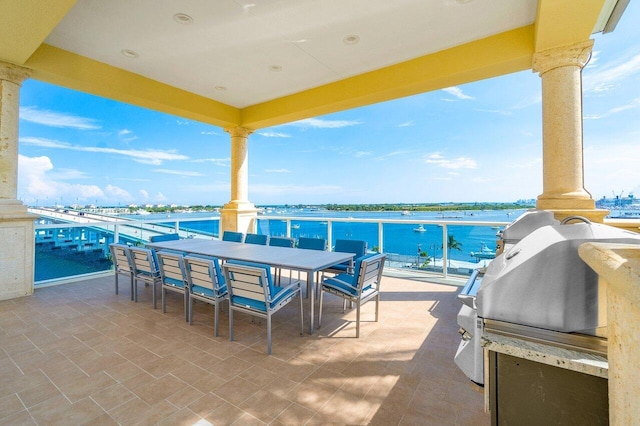 view of patio / terrace featuring a water view, an outdoor kitchen, and a balcony