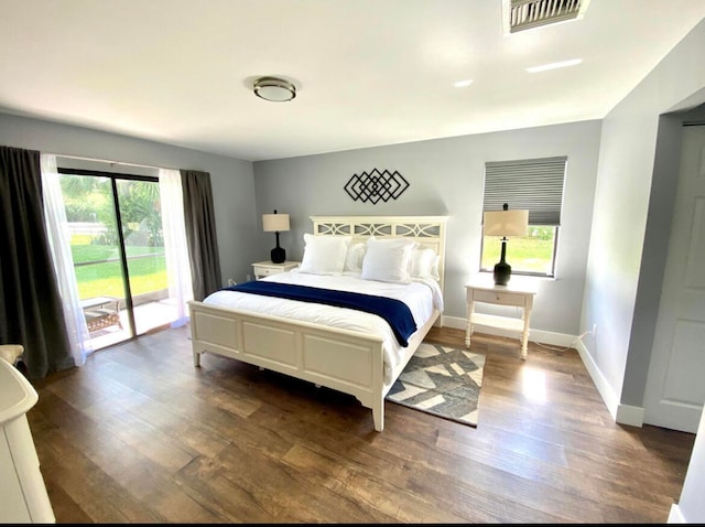 bedroom with access to outside, hardwood / wood-style floors, and multiple windows