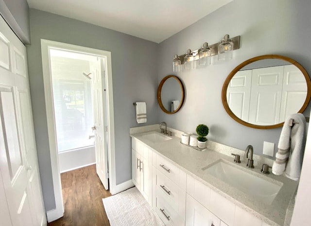 bathroom featuring hardwood / wood-style floors, double vanity, and bathing tub / shower combination