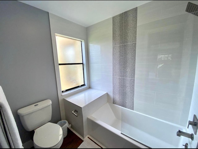 bathroom with toilet and tiled shower / bath